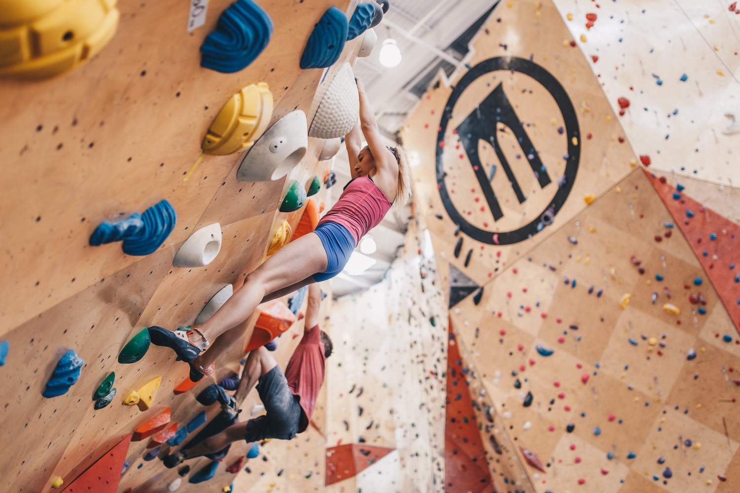 woman in pink shirt and blue shorts rock climbing